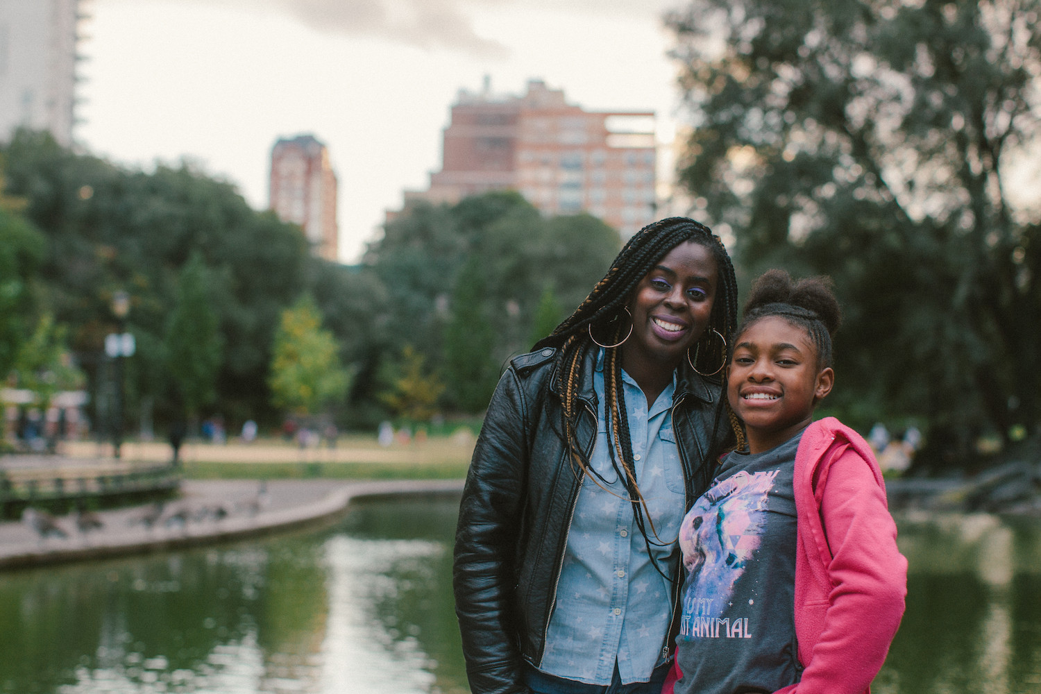 A mentor and her mentee pose for a photo by a pond in a park