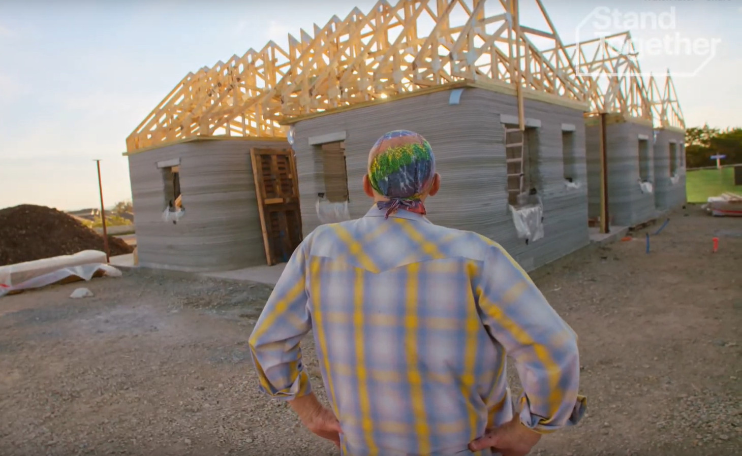 A man looks on at a 3D printed home in construction