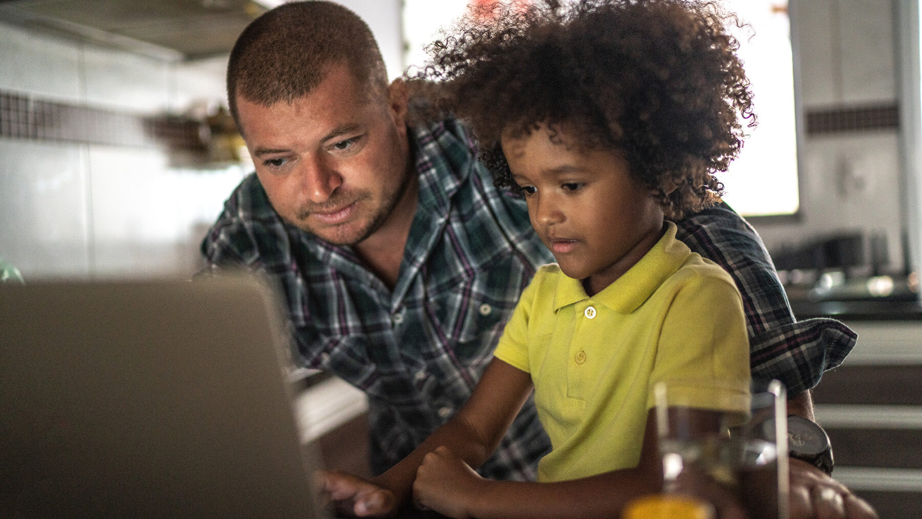 A man helping a child on a laptop
