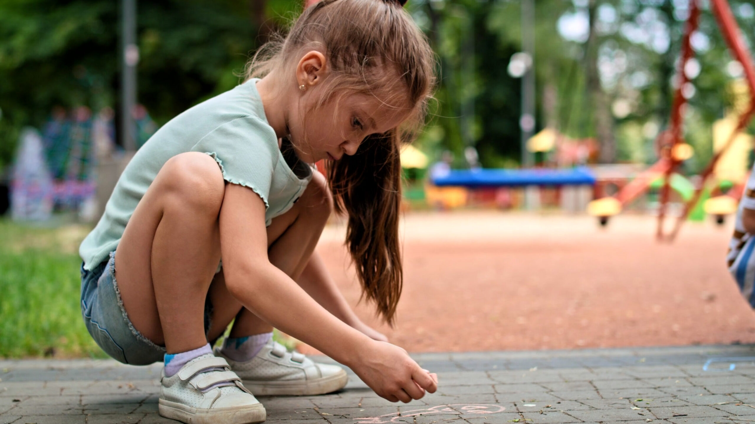 Child playing with chalk in a park