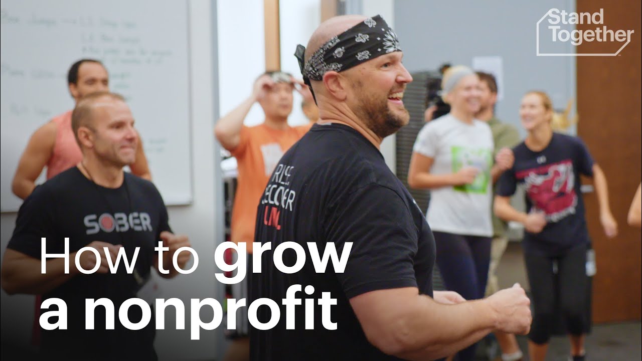 A group of people in casual workout attire laughing and interacting in a room, with a man in the foreground wearing a bandana and a "SOBER" t-shirt, and the text "How to grow a nonprofit" overlaying the image.