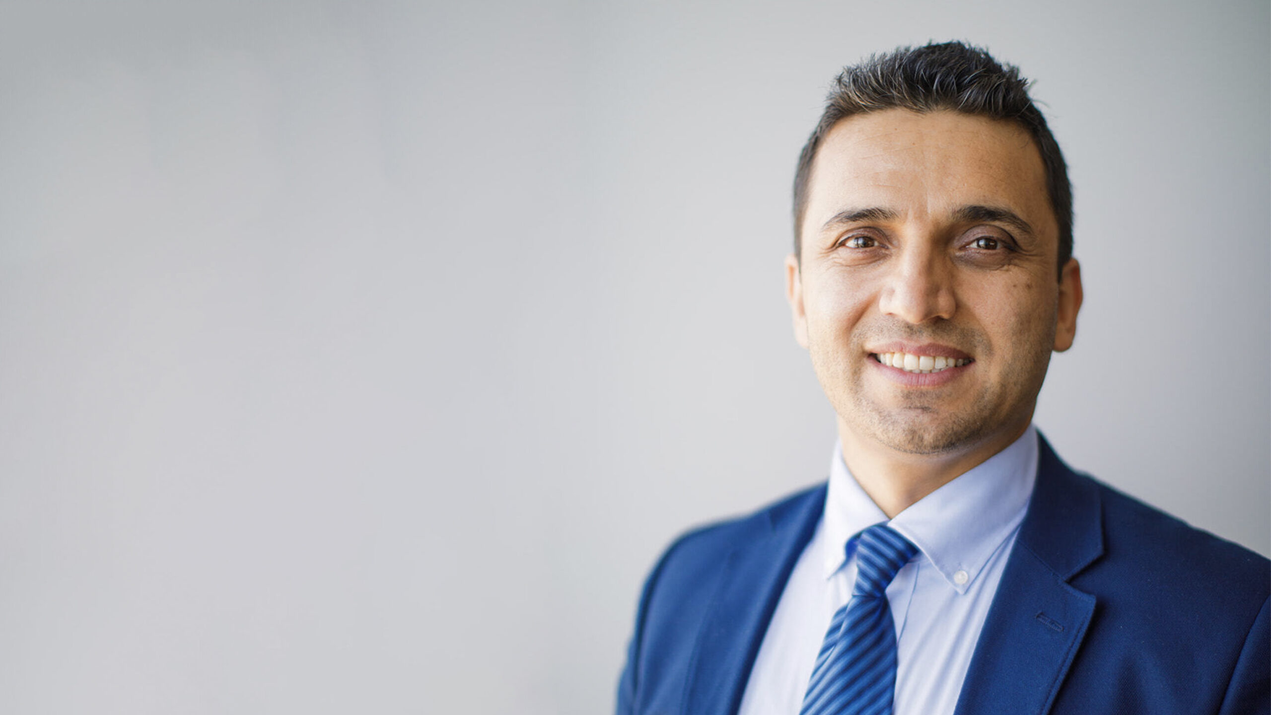 Shoaib Sahiby poses for a headshot in a navy blue suit