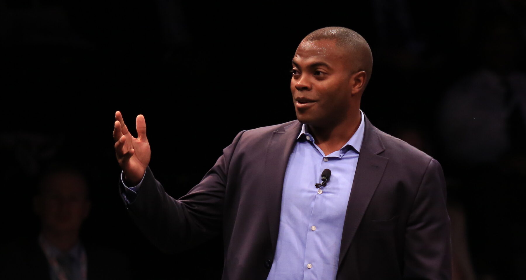 Man in suit gesturing on stage.