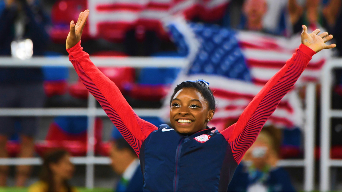 Simone Biles with her hands up at the Olympics